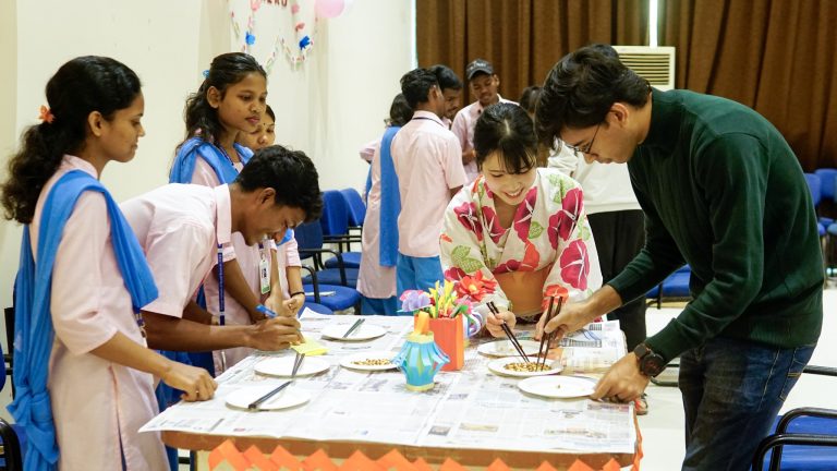 An international volunteer working with KISS students on a craft activity